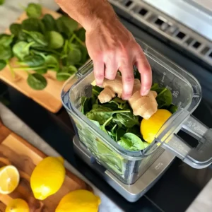 Adding lemon and ginger to blender with spinach