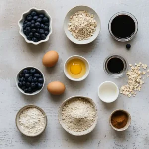 Protein-Packed Blueberry Coffee Cake Muffins Recipe for a Nourishing Morning Treat 5 Ingredients for protein-packed blueberry coffee cake muffins laid out on a wooden kitchen counter