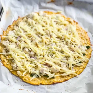Spreading chicken mixture into a pizza crust on baking sheet
